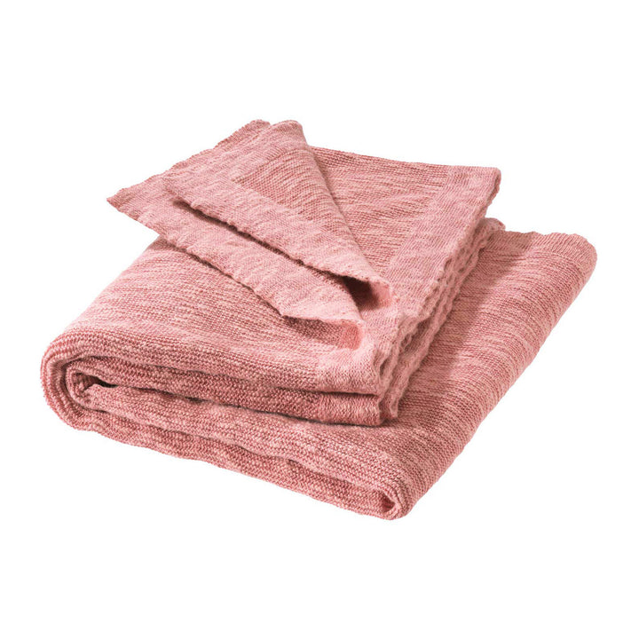Folded pink cotton linen Disana blanket on a white background