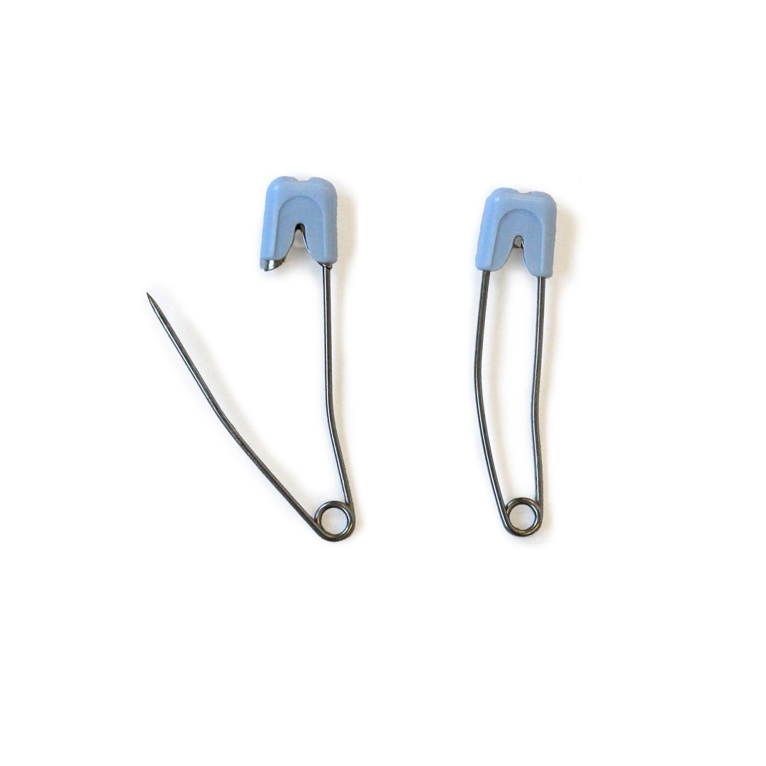 Two safety diaper pins pins with blue plastic tips on a white background