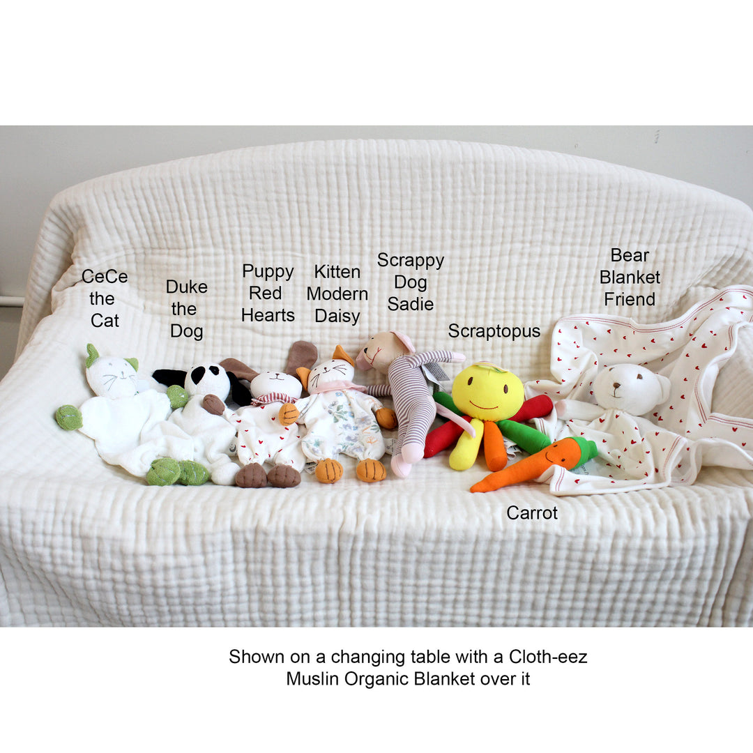 Collection of soft toys on a changing table with a Cloth-eez Muslin Organic Blanket