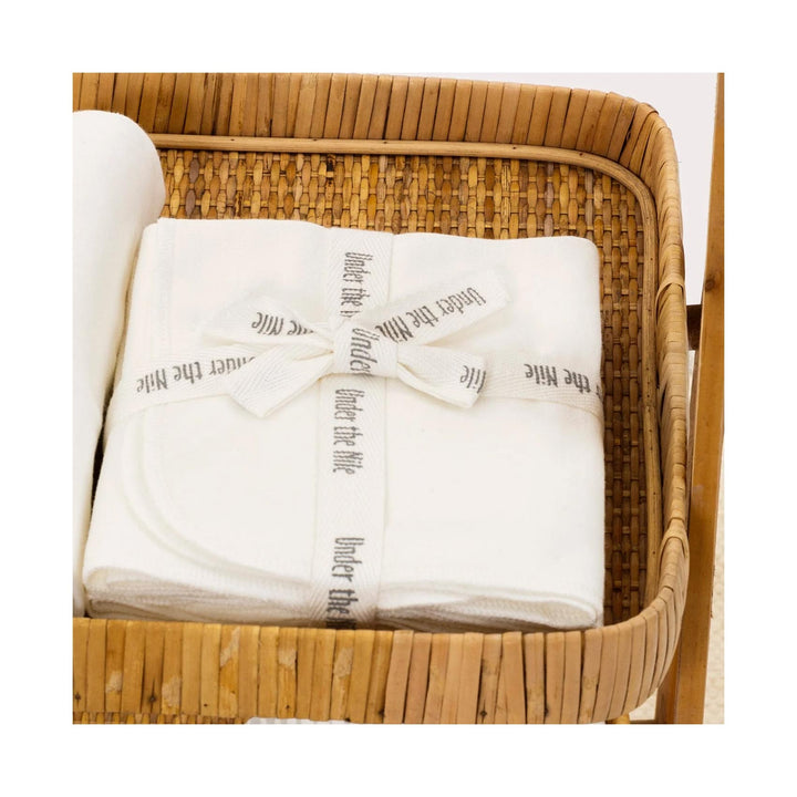 Folded white organic cotton burp cloths  in a wicker basket