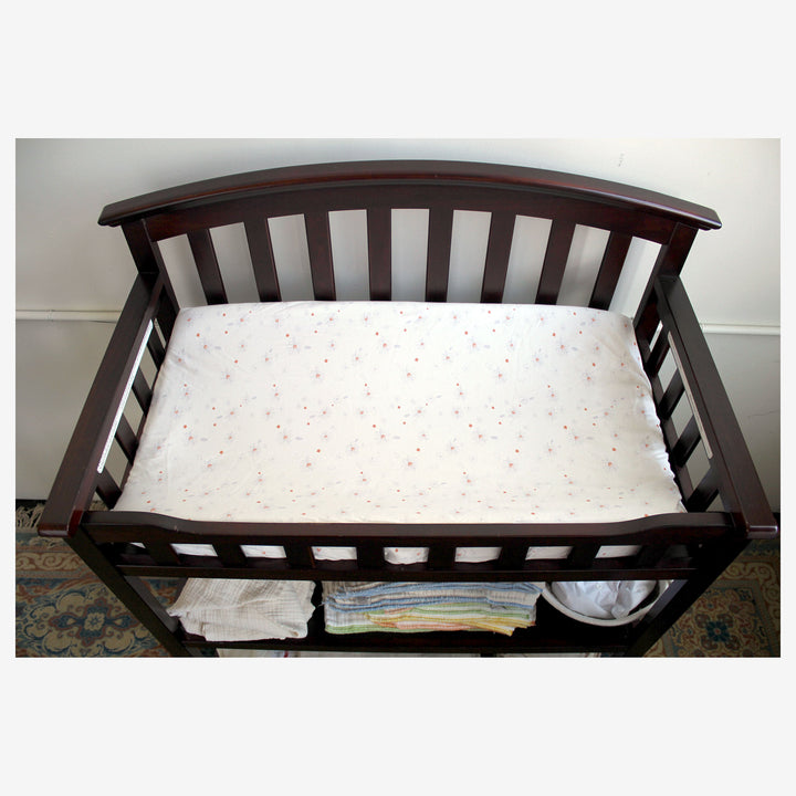 Wooden changing table with an organic cotton Under the Nile changing pad cover and  cloth diapers