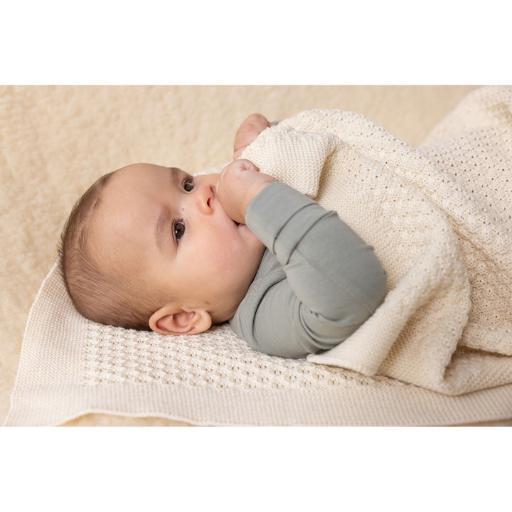 Baby wrapped in a Disana natural wool blanket honeycomb knit