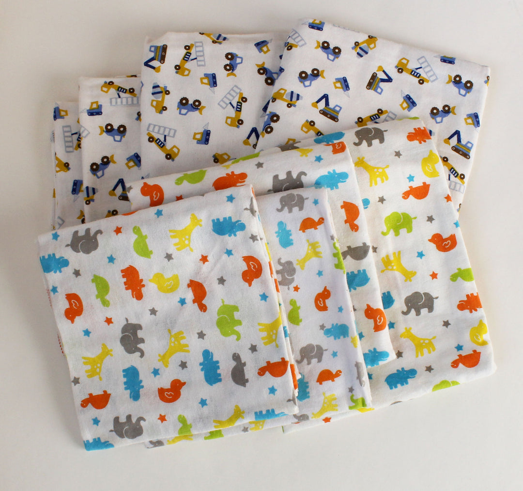 Set of folded fabric sheets with animal and vehicle patterns on a white background