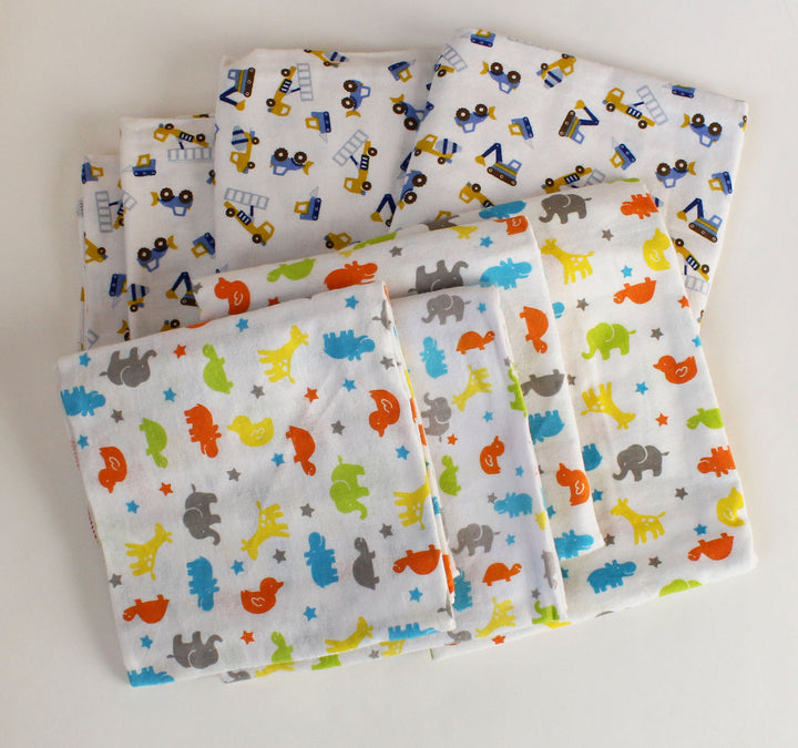Set of folded fabric sheets with animal and vehicle patterns on a white background
