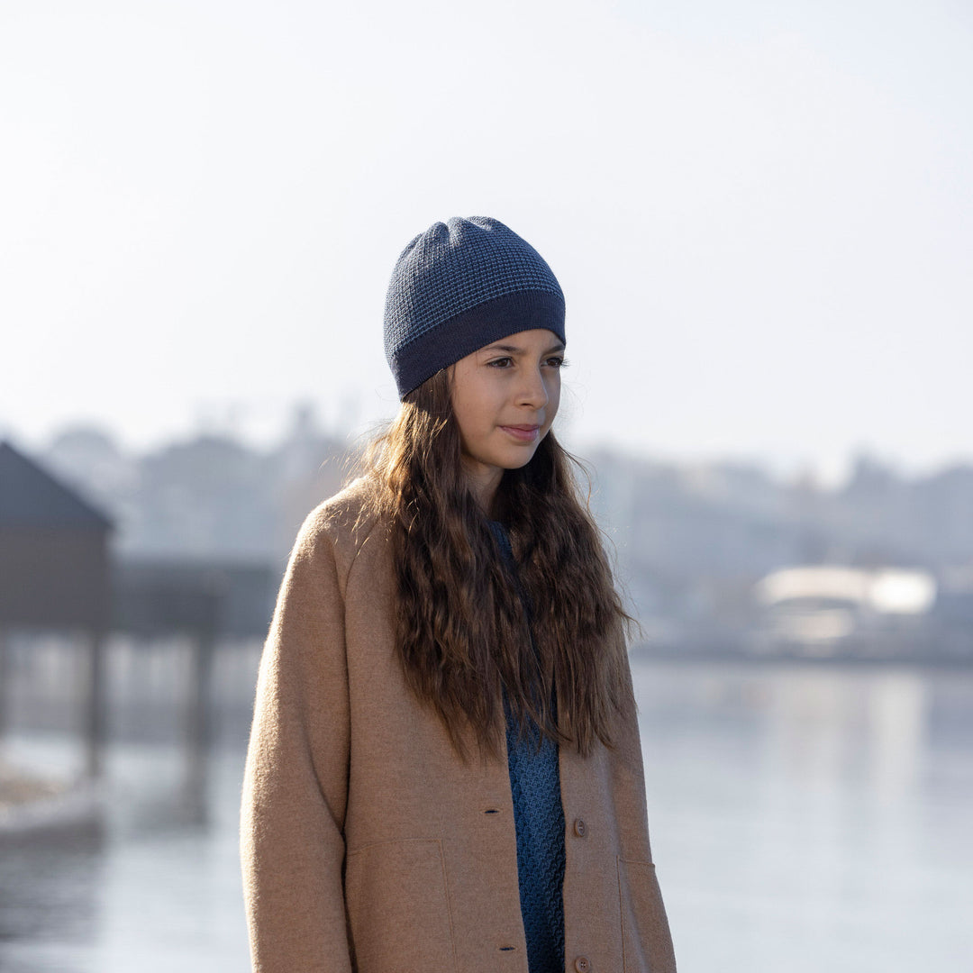 Woman wearing an organic wool knit beanie and coat by Disana