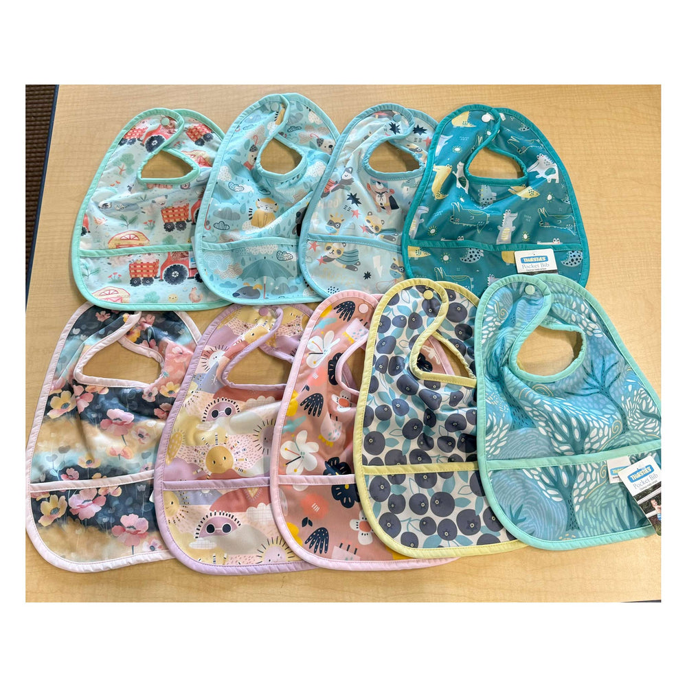 Set of colorful thirsties baby bibs on a wooden surface