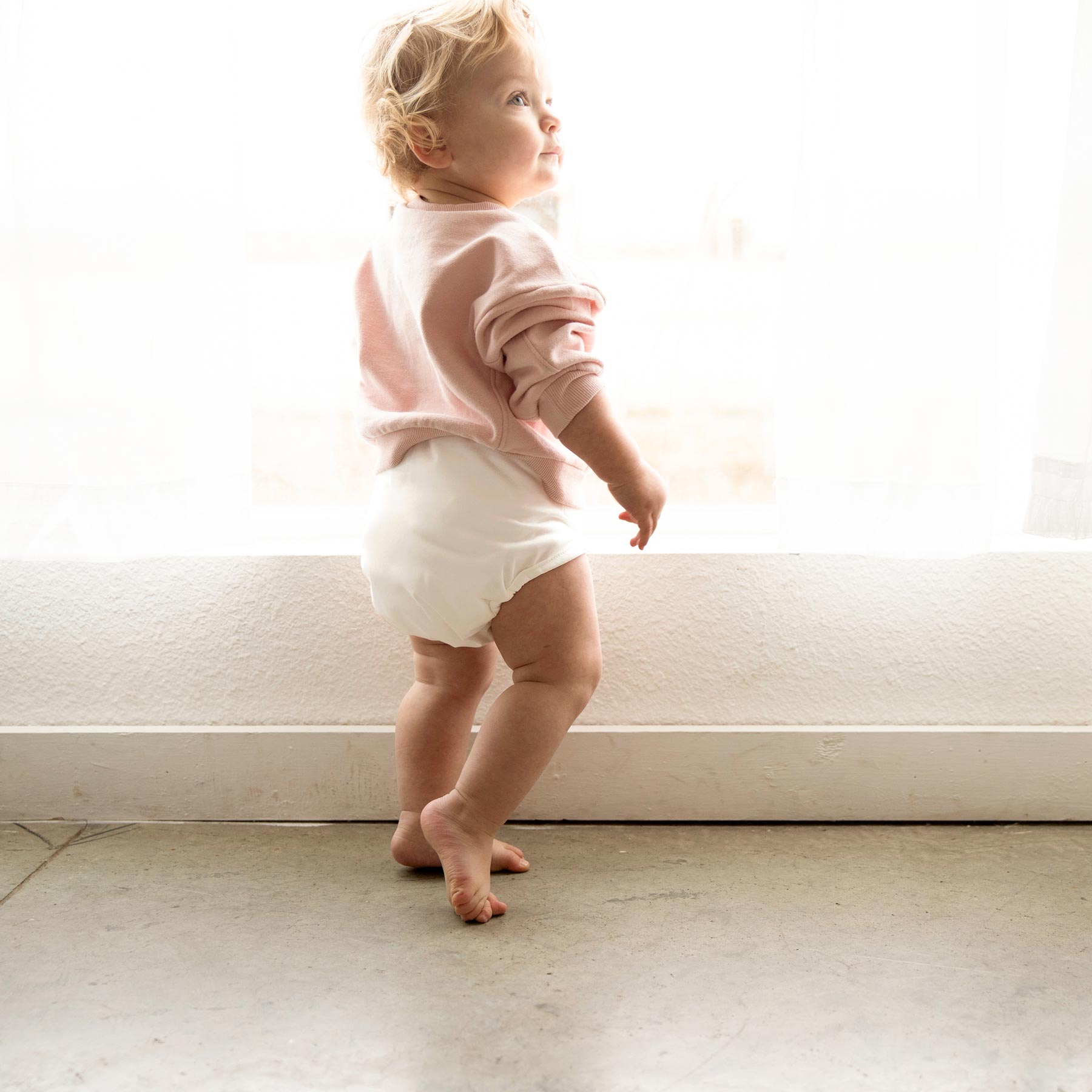 toddler standing in white cloth diaper cover