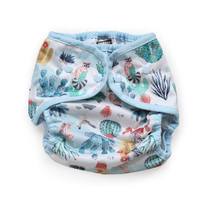 Thirsties Cover reusable cloth diaper with a light blue trim and a white background printed with a colorful Desert Dunes print size Large