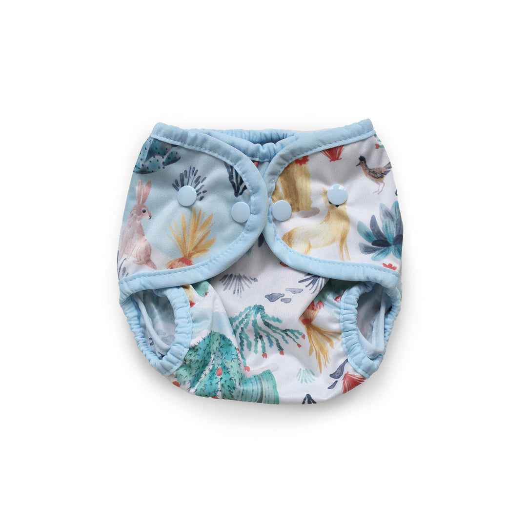 Thirsties Cover reusable cloth diaper with a light blue trim and a white background printed with a colorful woodland animal pattern Desert Dunes size newborn