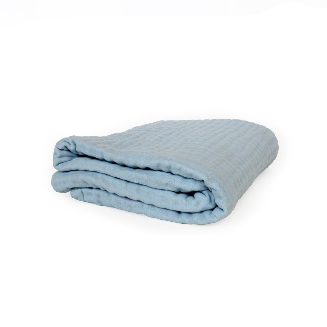 Folded light blue baby quilt on a white background