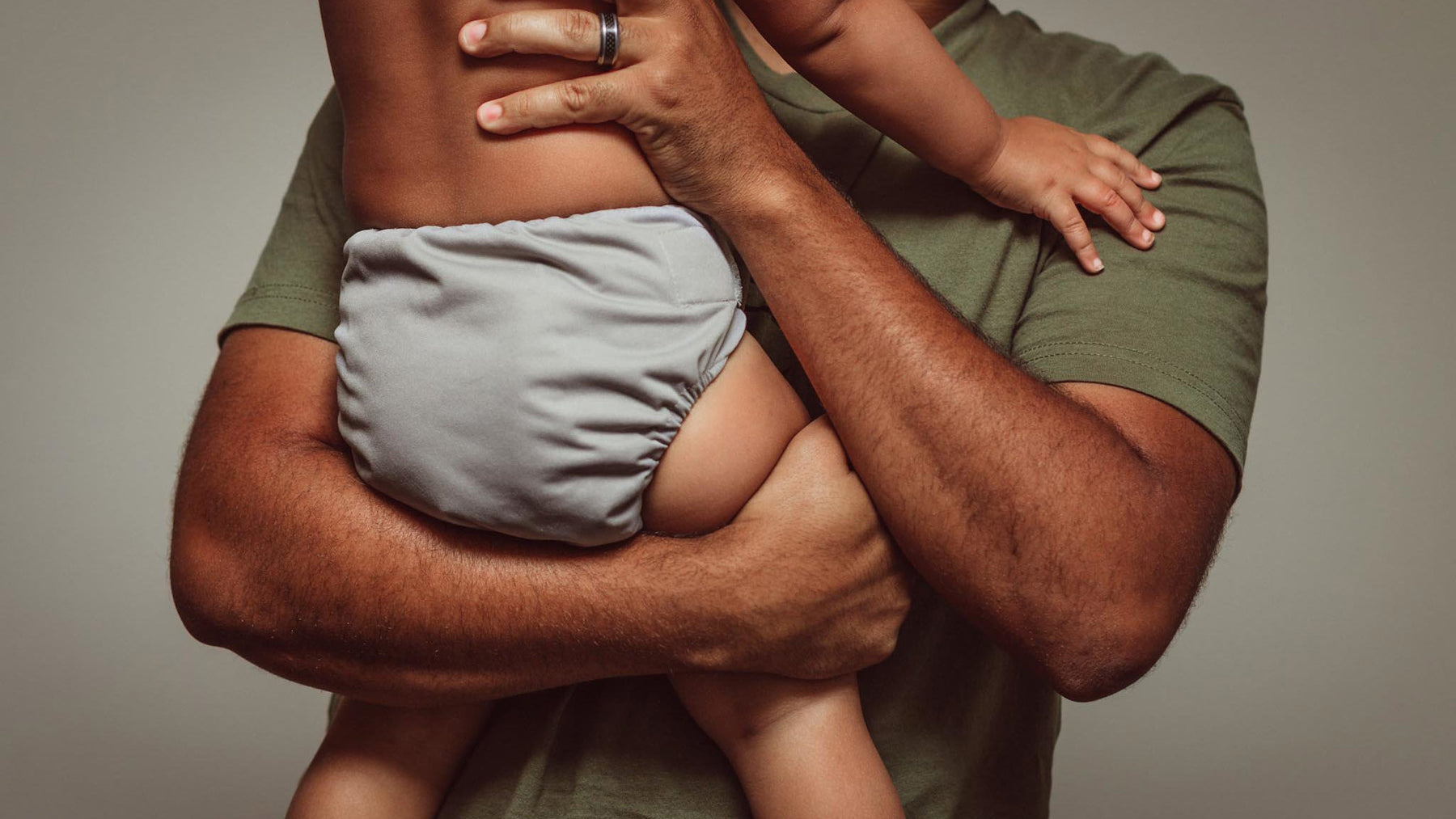 dad holding baby wearing a grey Thirsties all-in-one cloth diaper 