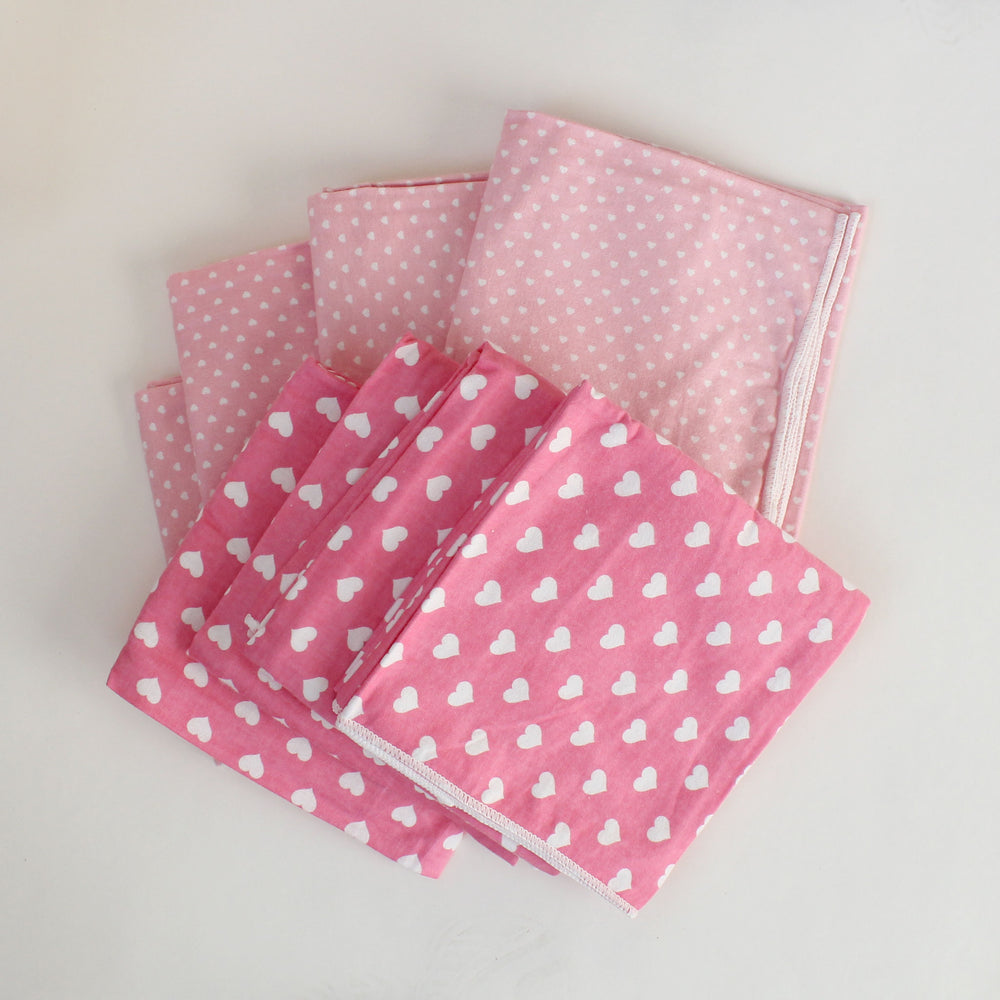 Set of pink fabric swatches with heart and polka dot patterns on a light gray background