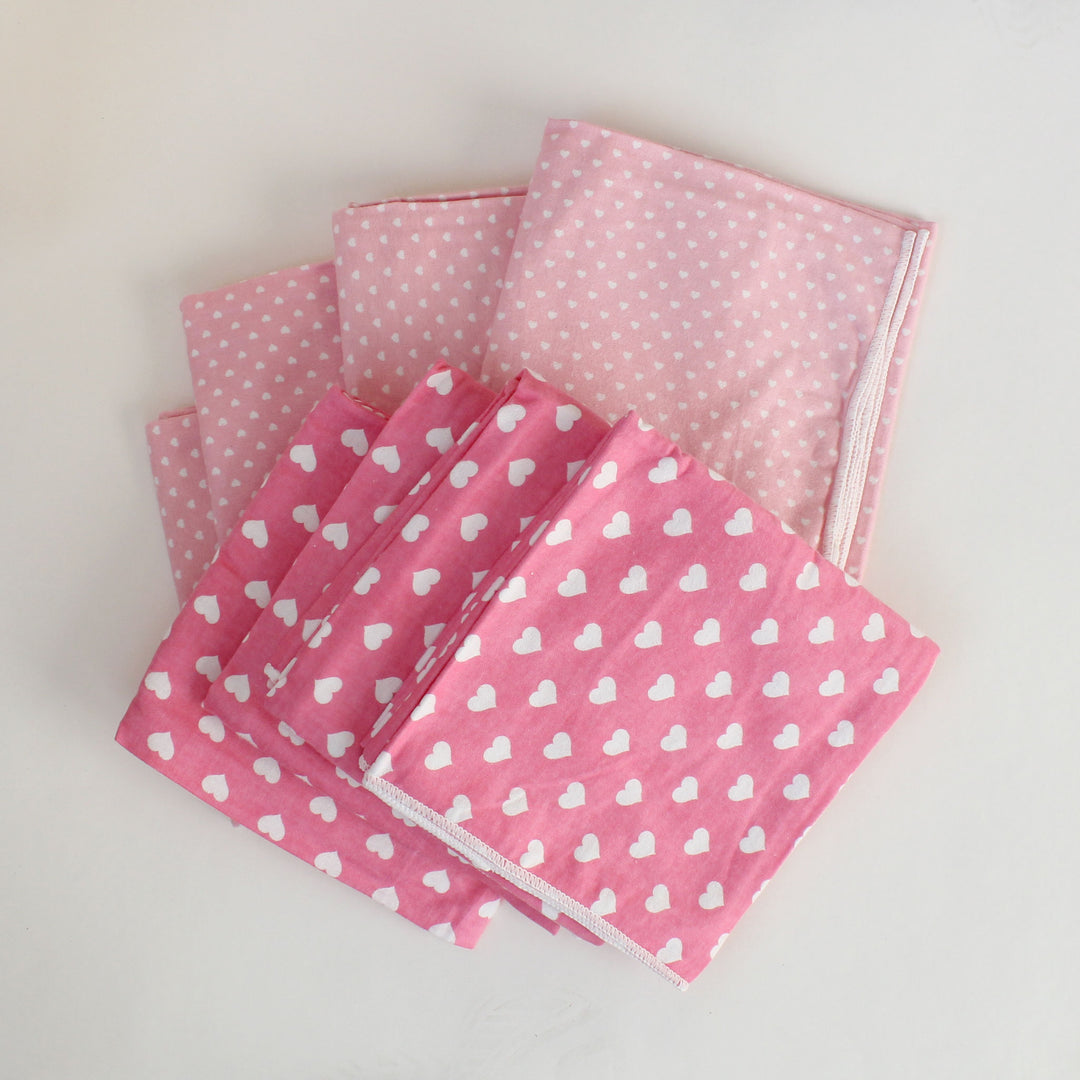 Set of pink fabric swatches with heart and polka dot patterns on a light gray background