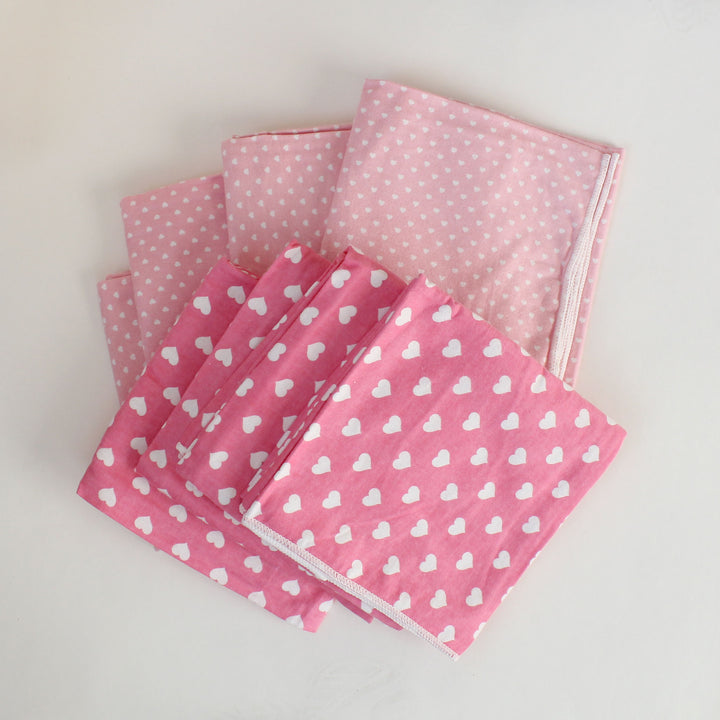 Set of pink fabric swatches with heart and polka dot patterns on a light gray background