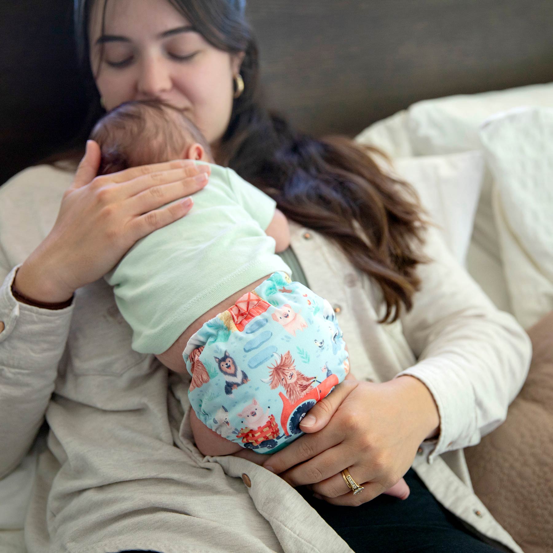 Mom holding newborn baby in a farm print Thirsties cloth diaper