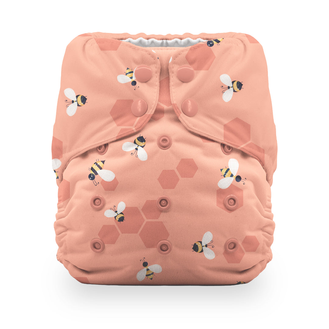 Thirsties reusable cloth diaper in a peach-pink color with a pattern of honeycomb hexagons and bumblebees Let it Bee print
