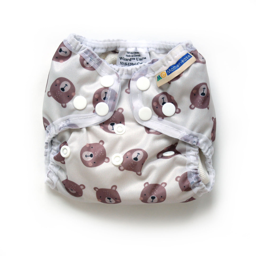A reusable cloth diaper with a white background and a brown teddy bear pattern, featuring three snap closures Mother-ease Wizard Uno Xs newborn