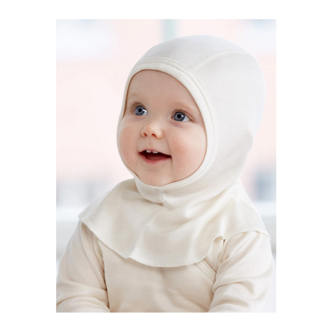 Baby wearing a white silk hood Ruskovilla Balaclava