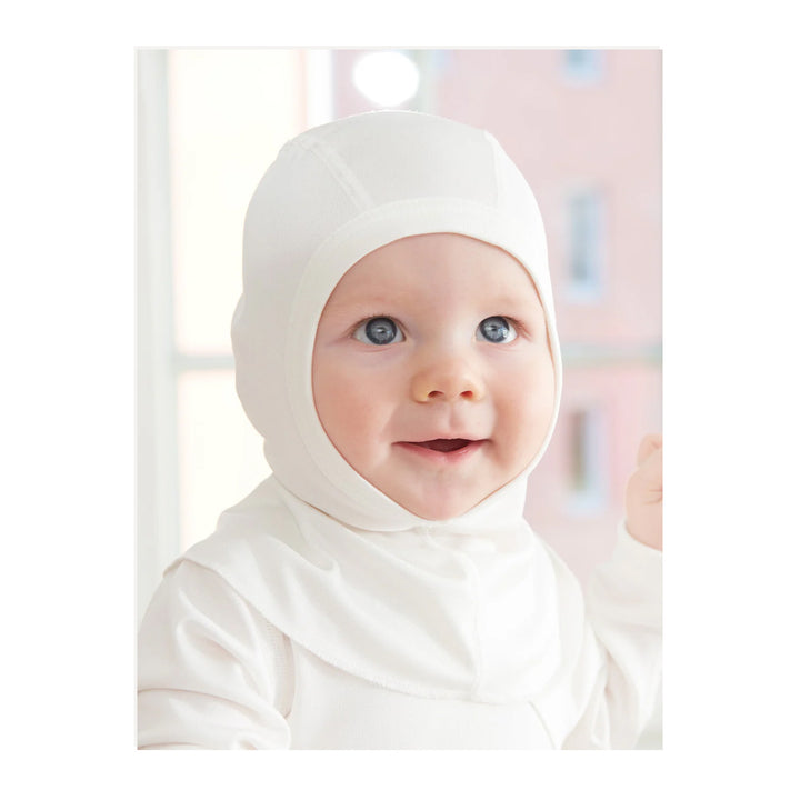 Baby wearing a white silk hood Ruskovilla Balaclava