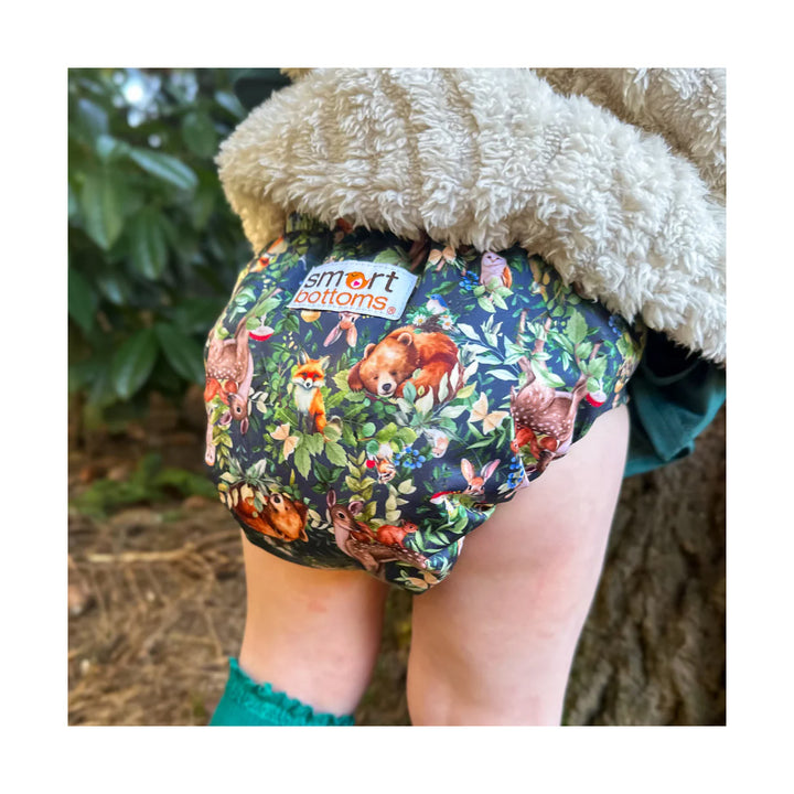 Floral-patterned diaper with 'smart bottoms' label worn by a toddler, against a natural background.