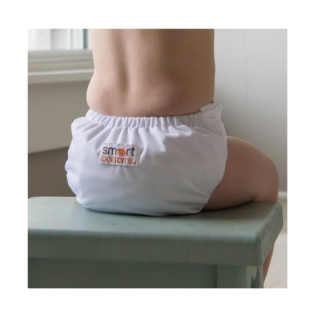White diaper with 'smart bottoms' logo on a child sitting on a step.