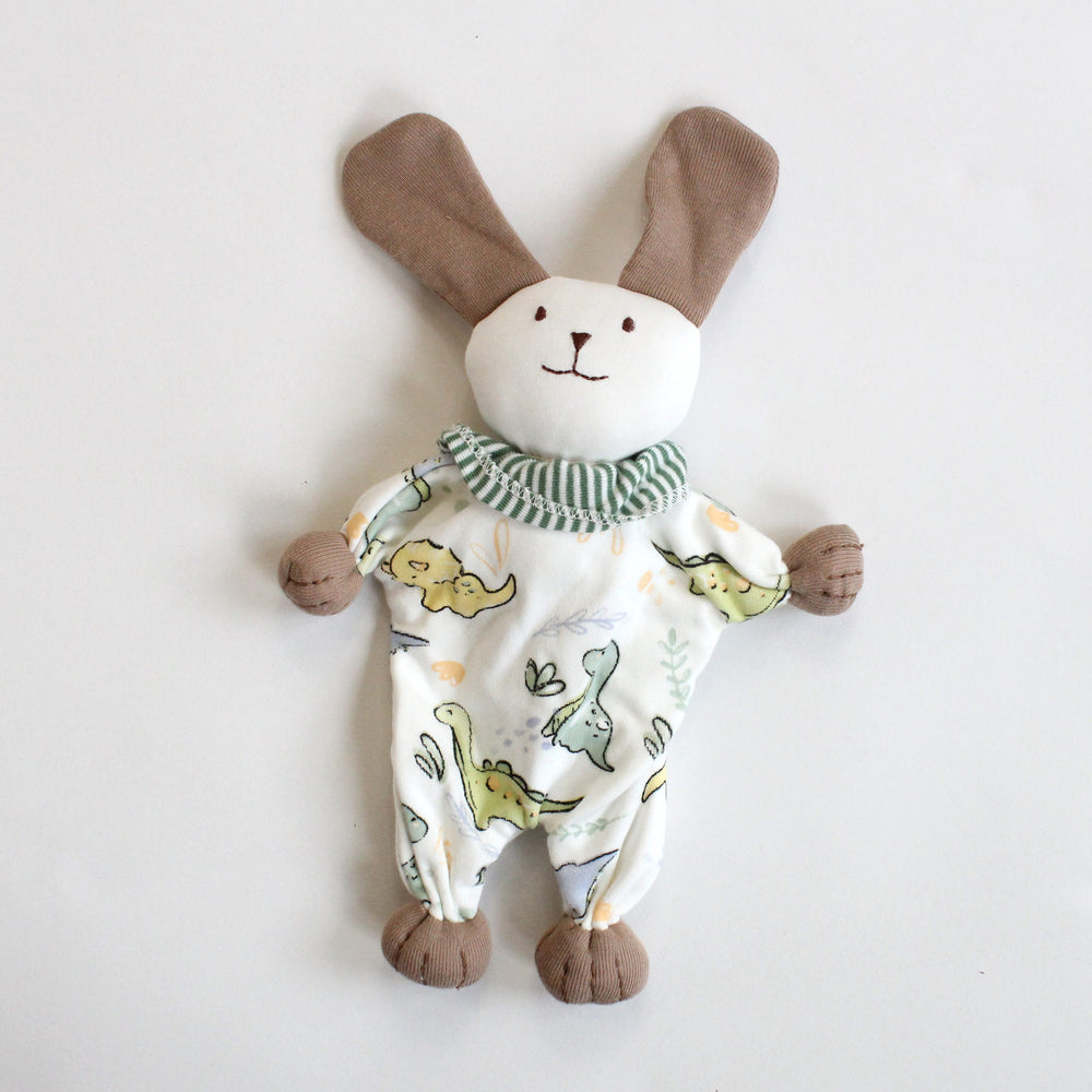 Organic cotton Stuffed toy puppy wearing a onesie with dinosaur print on a white background